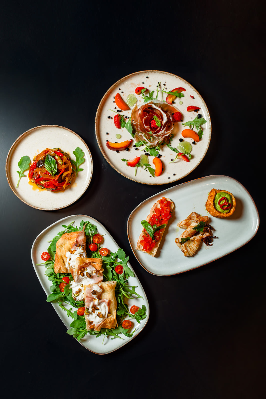 Quatre assiettes dressées vues du dessus — restaurant La Nonna